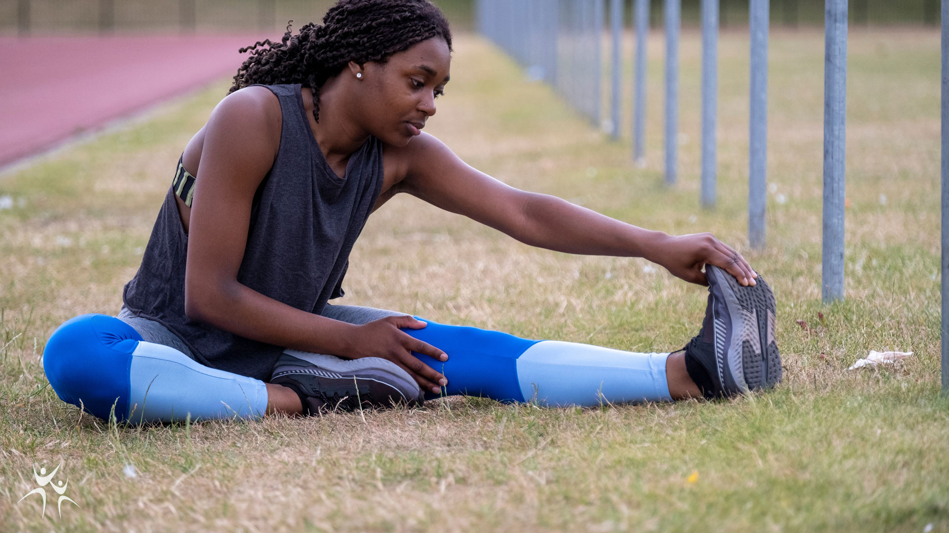 athlete sitting on ground stretching to warm up before a run