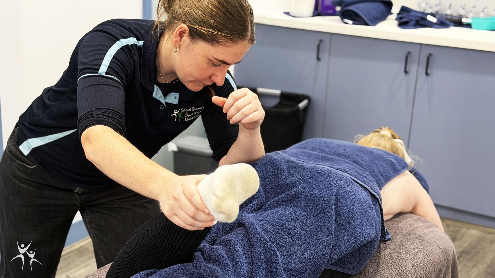 Osteo Meave Bohanna treating footy player's leg  as they lay on the treatment bed