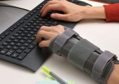 Closeup of person typing on a keyboard with one arm in a splint to support injury