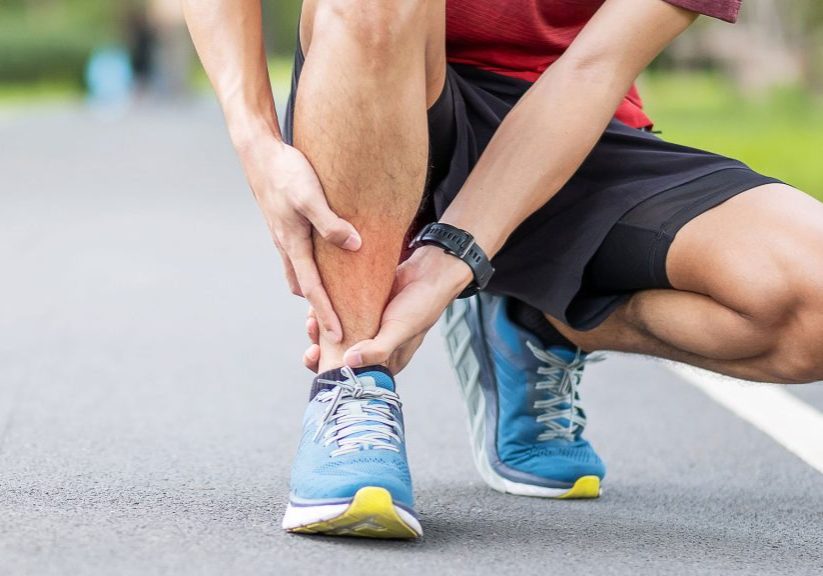 Person crouched down holding ankle in pain from a running injury