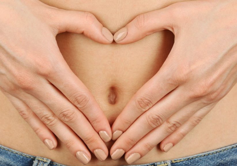 close up of woman  making a heart shape over her pregnant belly