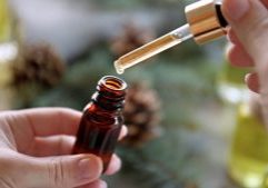 person holding a dropper into a bottle of massage oil