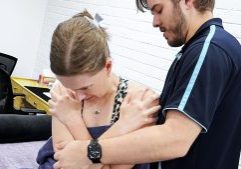 Dr Mitchell Pontefract examines seated client examining her spine